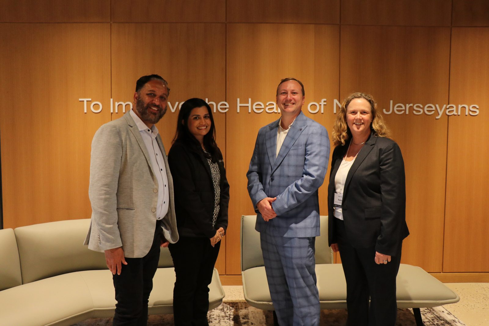 Genzeon Platforms at the NJ Hospital Association Medicare and Managed Care Summit, photographed beside the NJHA mission wall reading 'To Improve the Health of New Jerseyans'